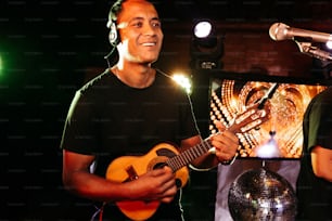 Un hombre sosteniendo una guitarra frente a un micrófono