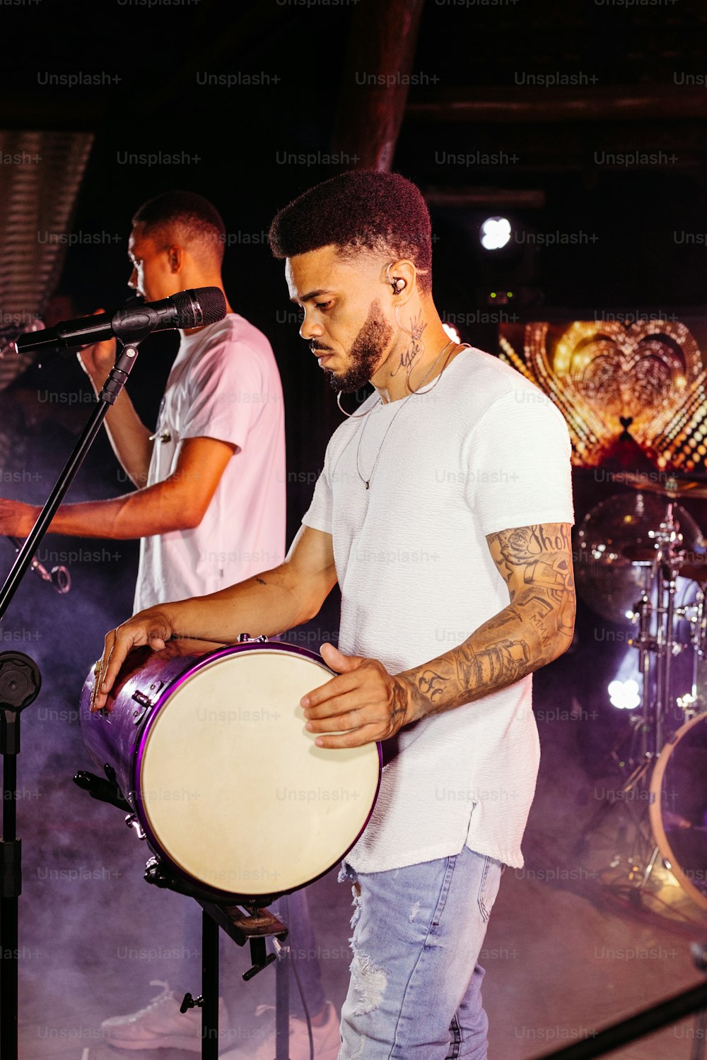 Un hombre sosteniendo un tambor frente a un micrófono