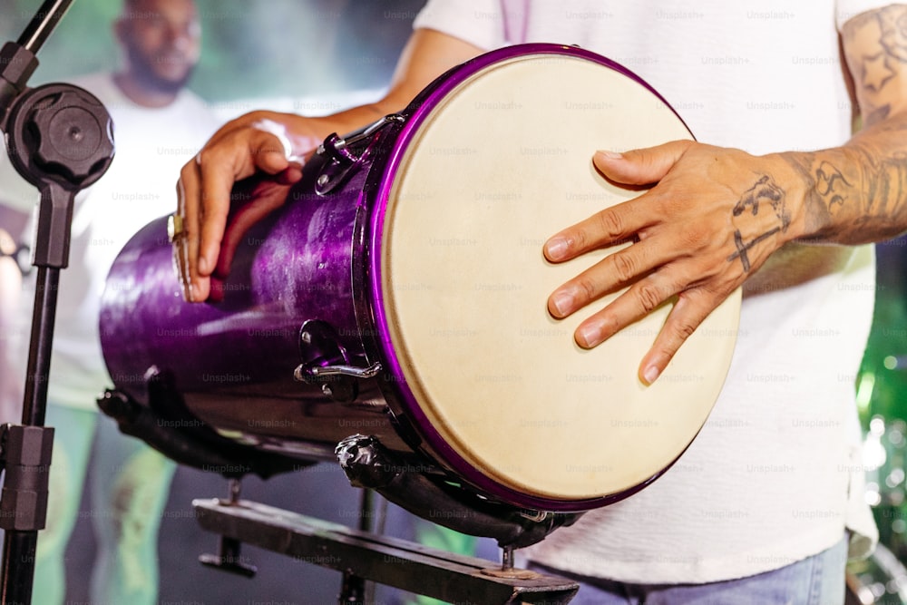 a man holding a purple drum in front of a microphone
