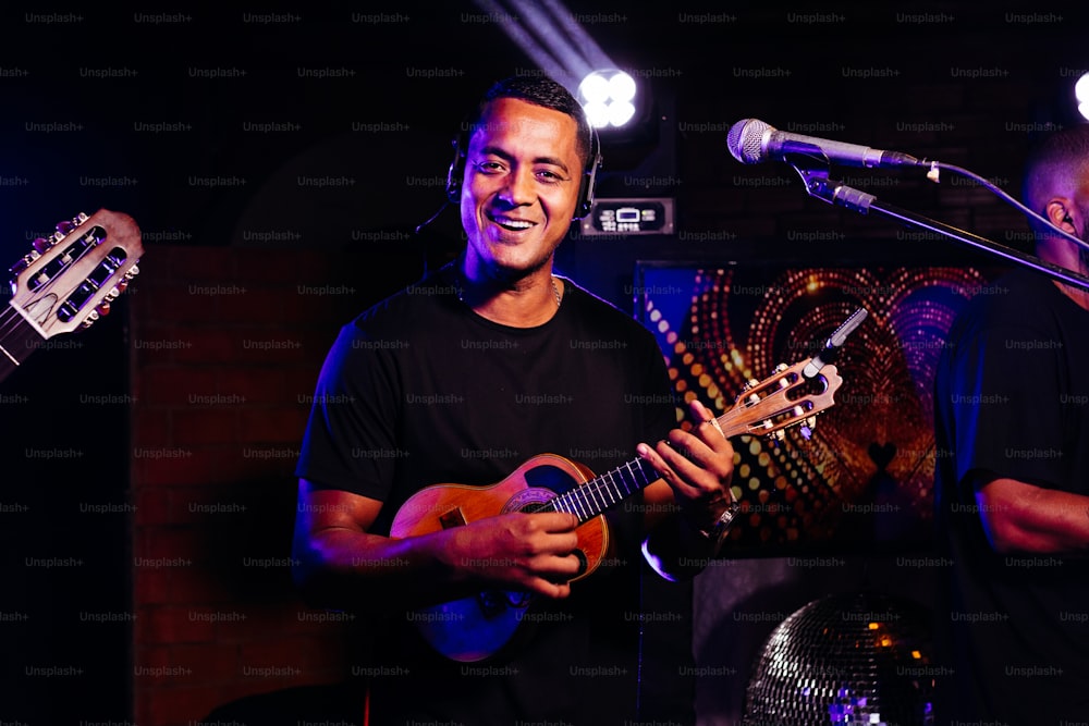 Un hombre sosteniendo una guitarra frente a un micrófono