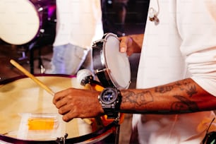 a man with a wrist tattoo playing a drum
