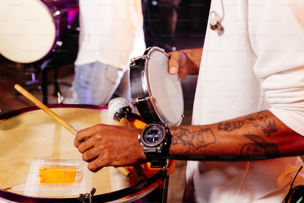 a man with a wrist tattoo playing a drum