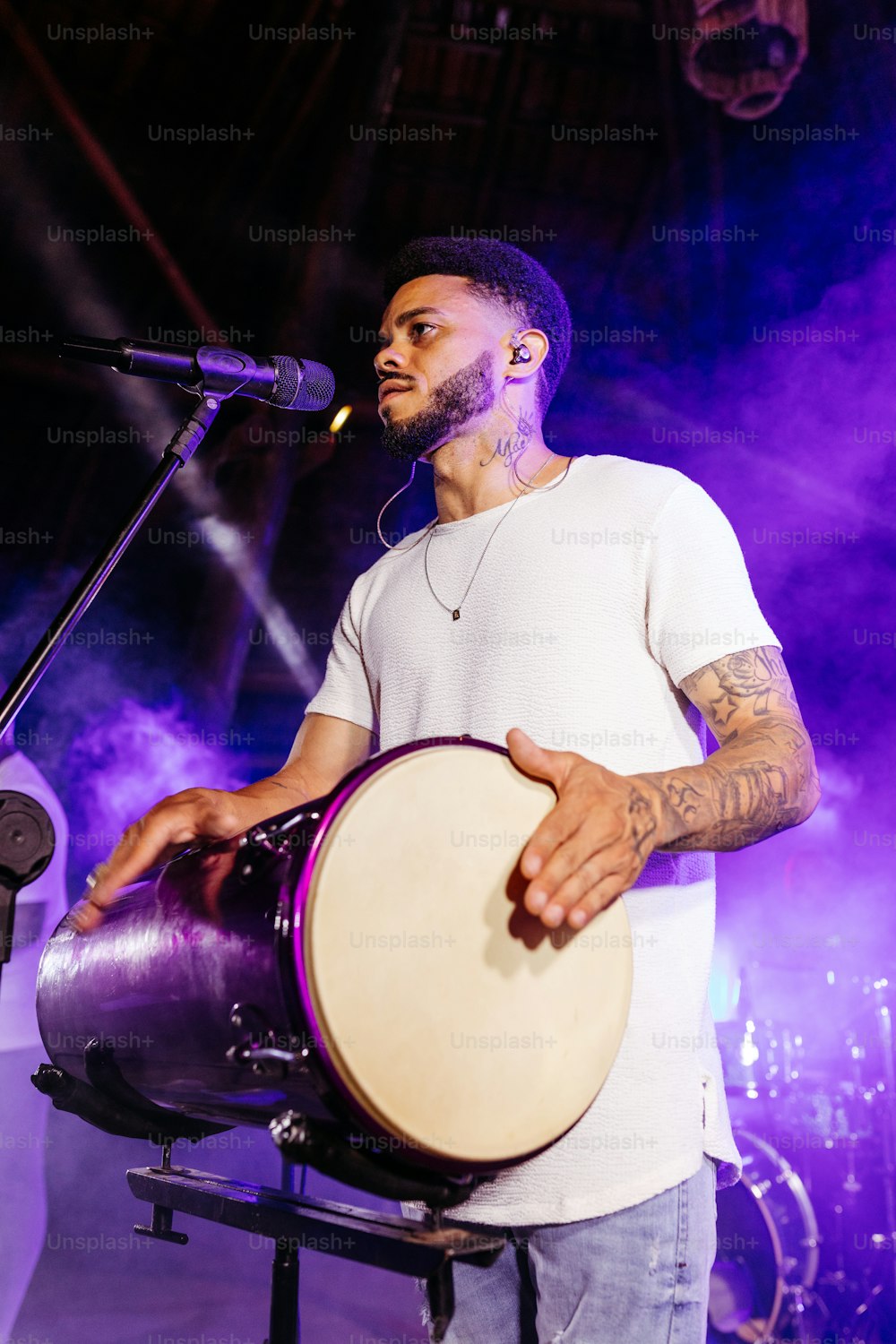 a man holding a drum in front of a microphone