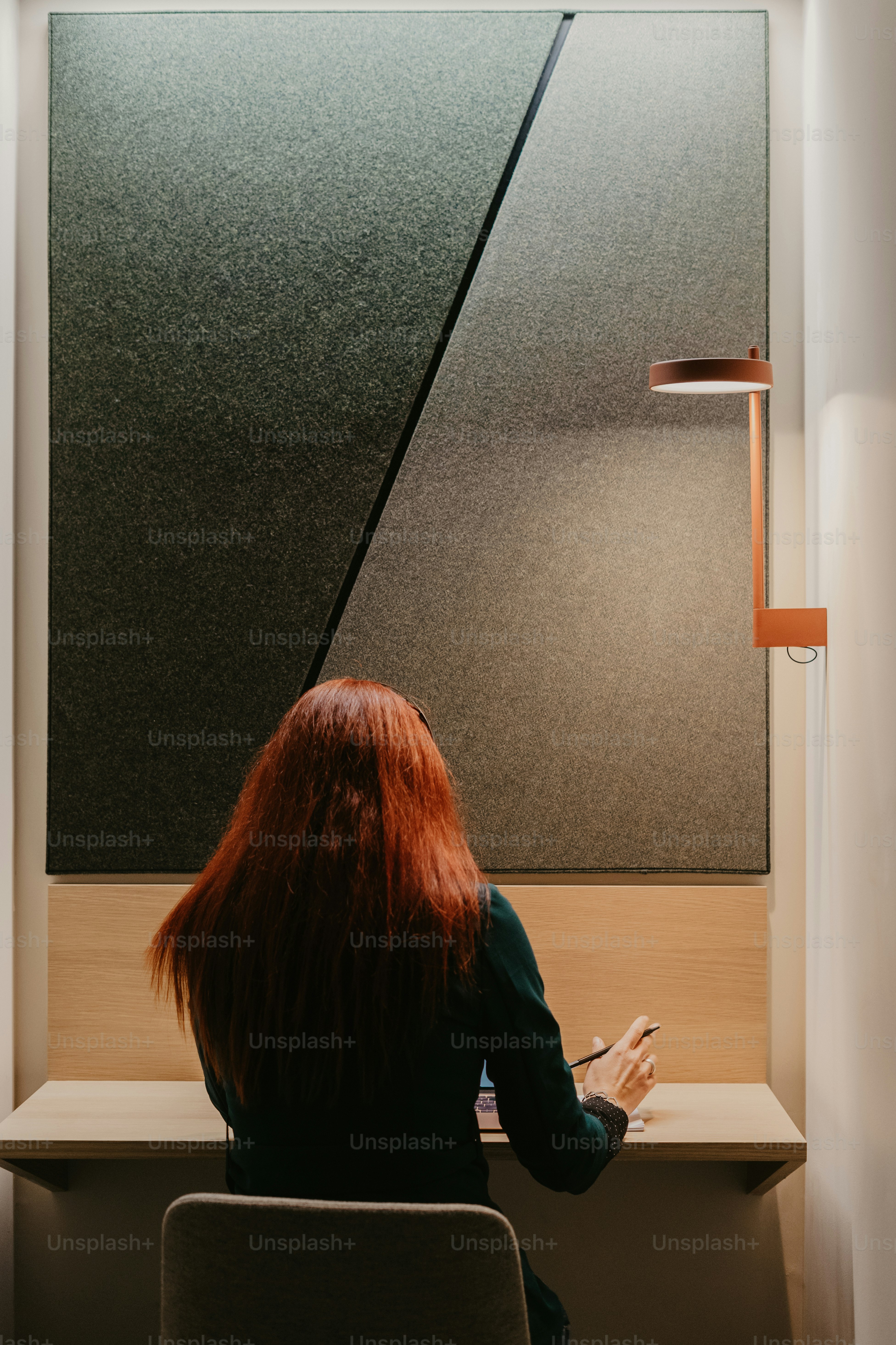 a woman sitting in a chair looking at a lamp