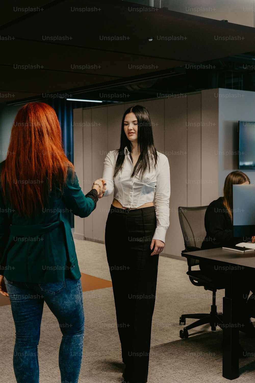 two women shaking hands in an office setting