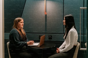 two women sitting at a table talking to each other