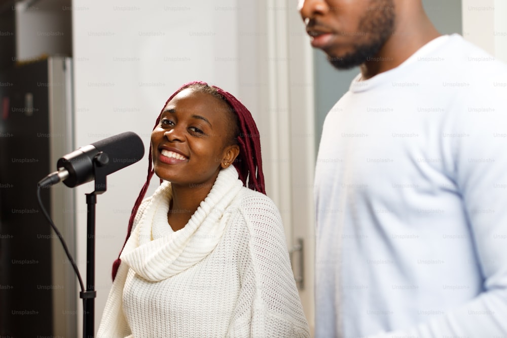 a man standing next to a woman in front of a microphone