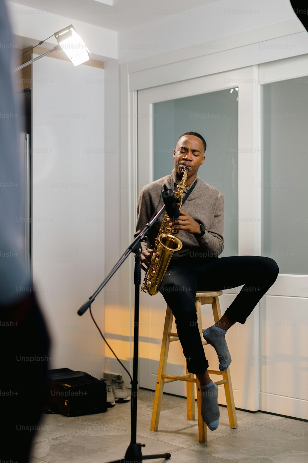 a man sitting on a stool playing a saxophone