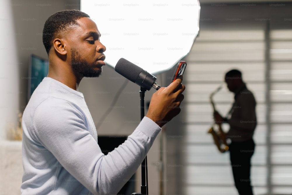 a man holding a microphone and looking at a cell phone