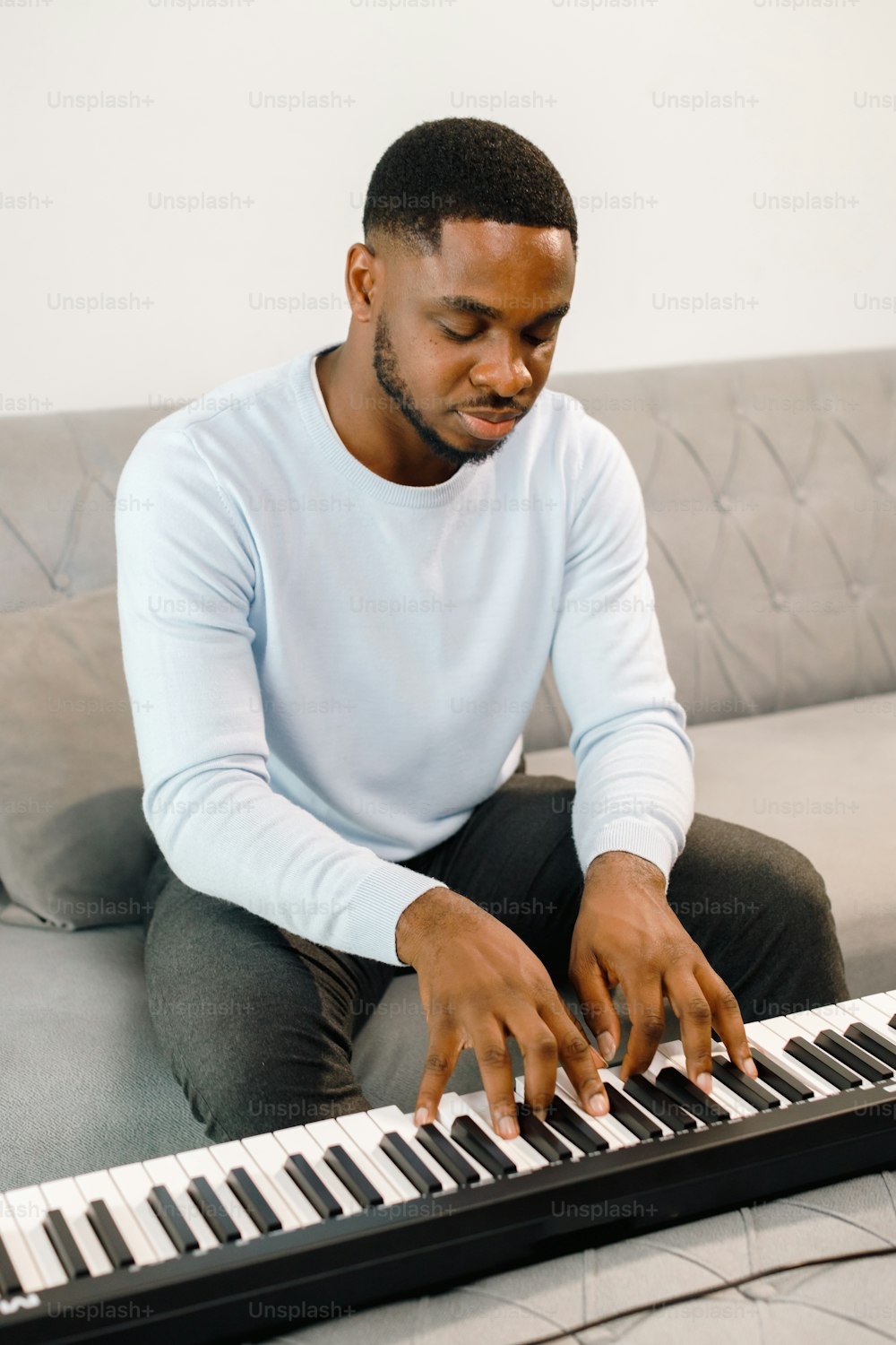a man sitting on a couch playing a keyboard
