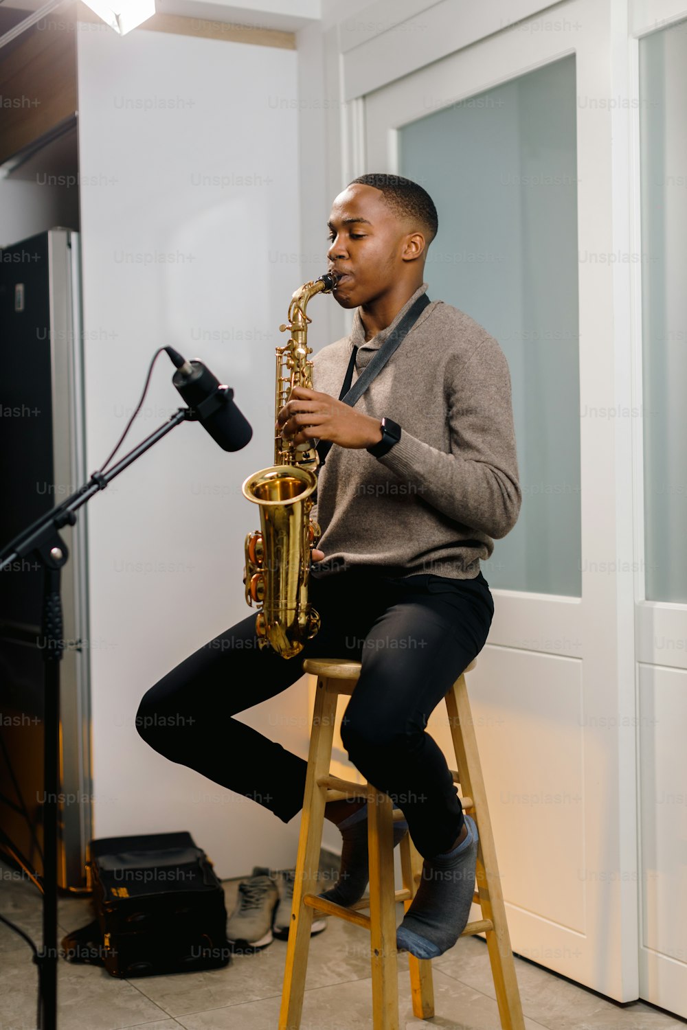 a man sitting on a stool playing a saxophone