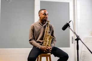 a man sitting on a stool holding a saxophone