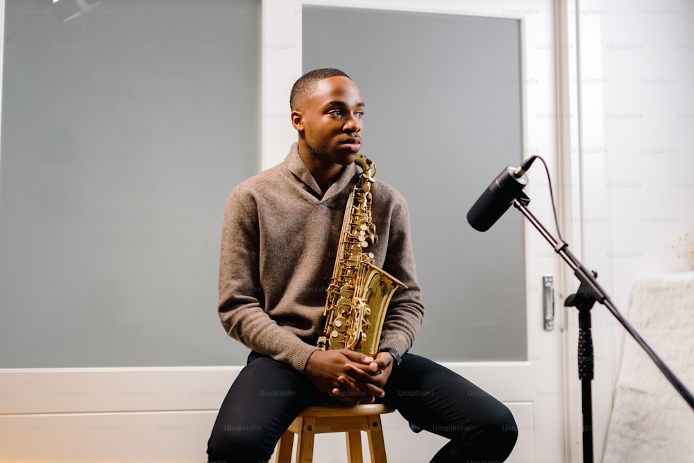 a man sitting on a stool holding a saxophone