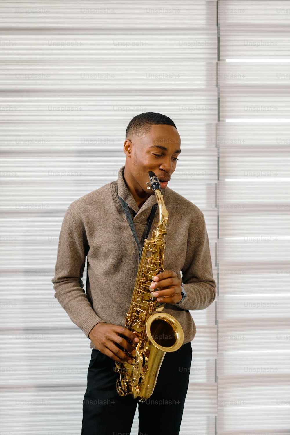 a man playing a saxophone in front of a white wall