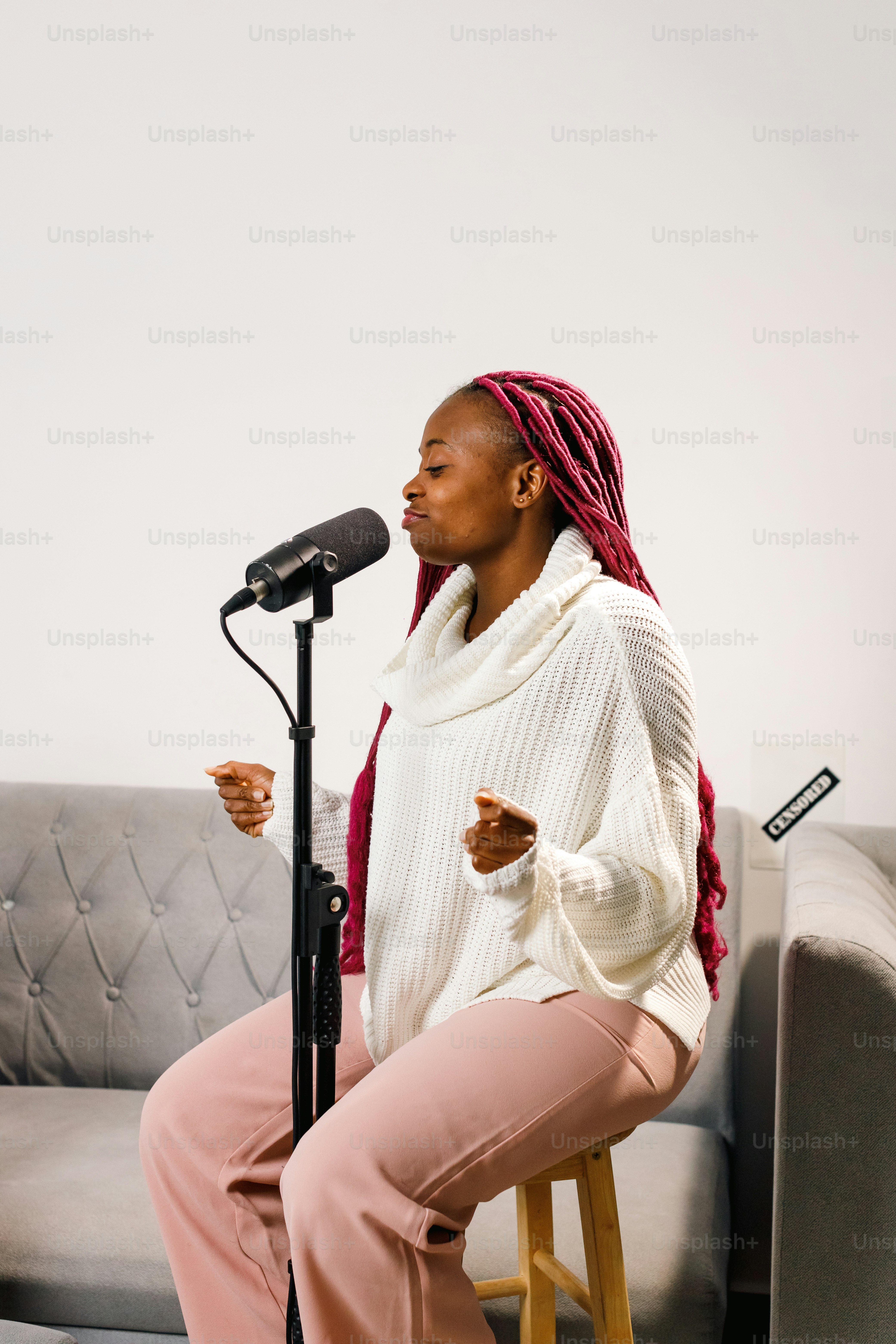 a woman sitting on a stool in front of a microphone