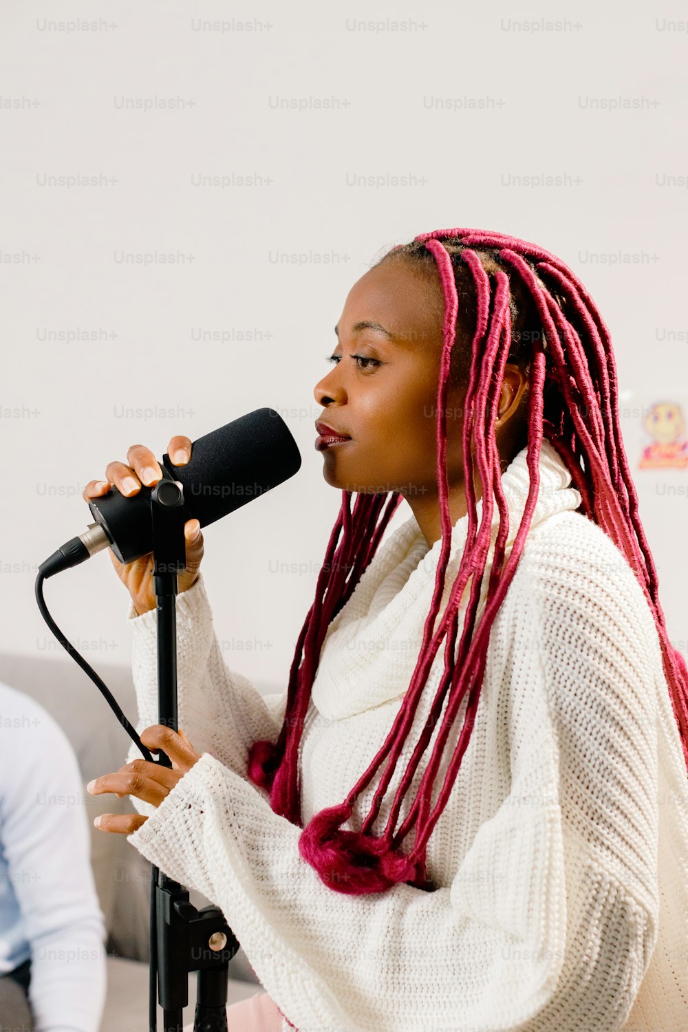 a woman with red dreadlocks is singing into a microphone