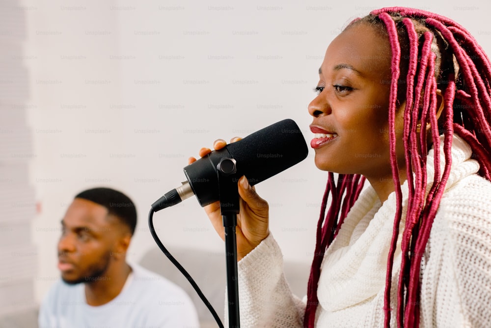 a woman with pink dreadlocks sings into a microphone