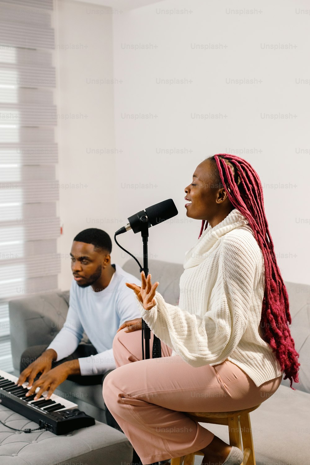 a man and a woman sitting on a couch in front of a microphone