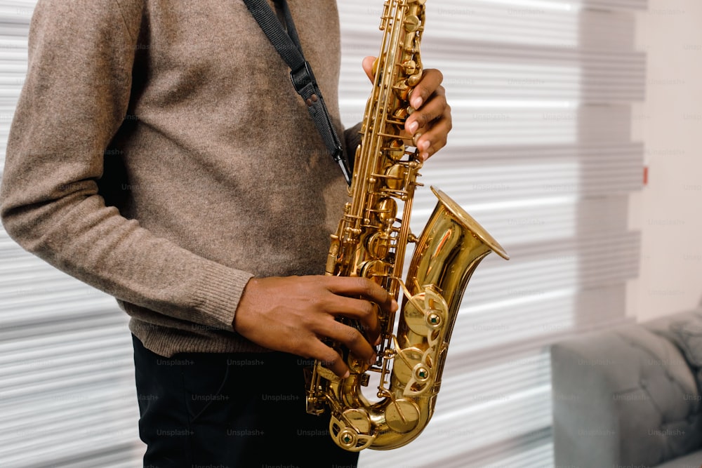 Un hombre sosteniendo un saxofón en su mano derecha