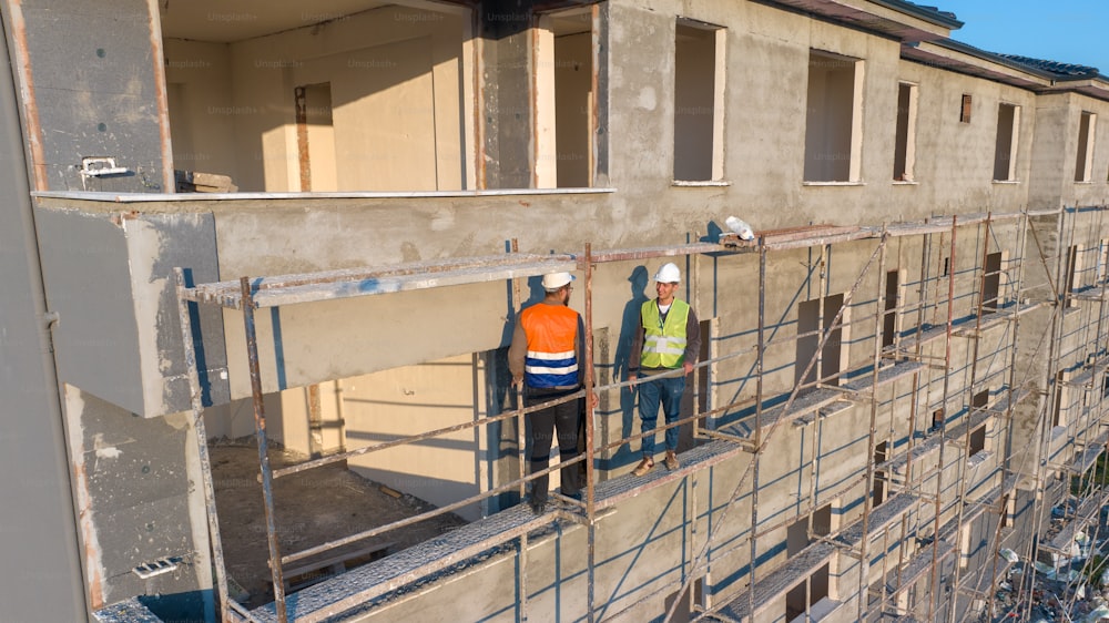 a couple of men standing next to each other on a scaffold