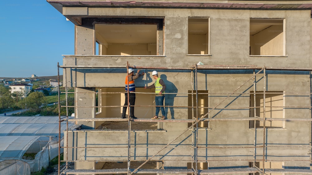 a couple of people standing on a scaffold in front of a building