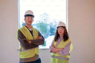 a man and a woman in hardhats standing in front of a window