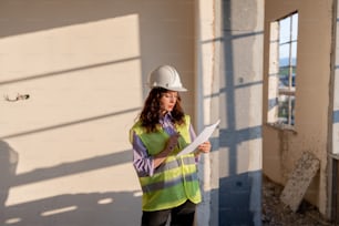 a woman in a hard hat is holding a piece of paper