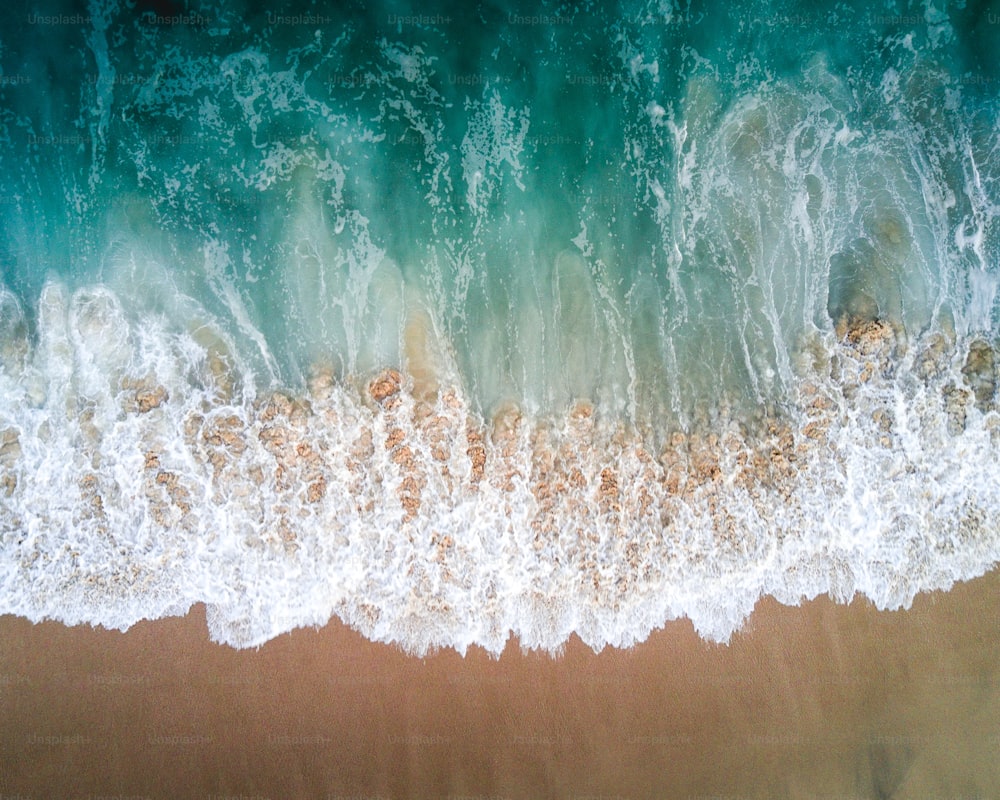 Eine Luftaufnahme eines Strandes mit Wellen, die darauf stürzen