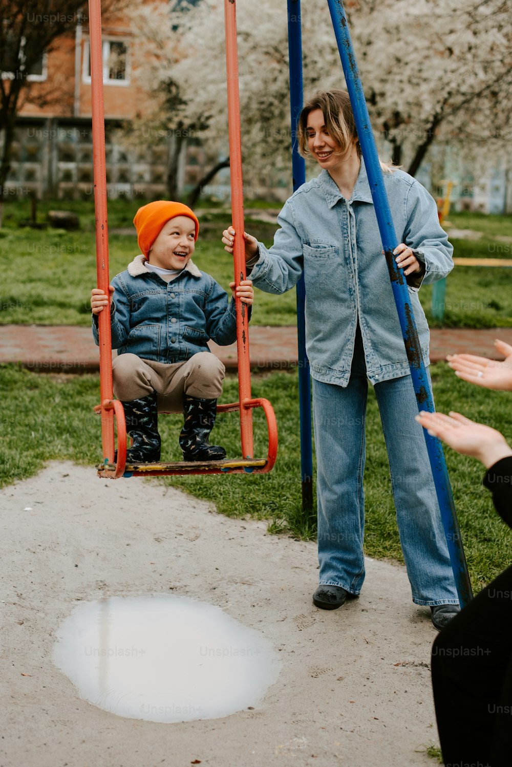 a woman standing next to a child on a swing