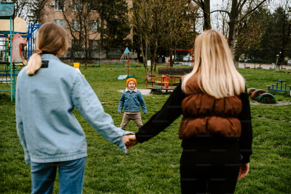 a woman holding a child's hand in a park