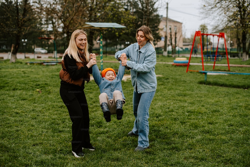 a woman and two children playing in a park