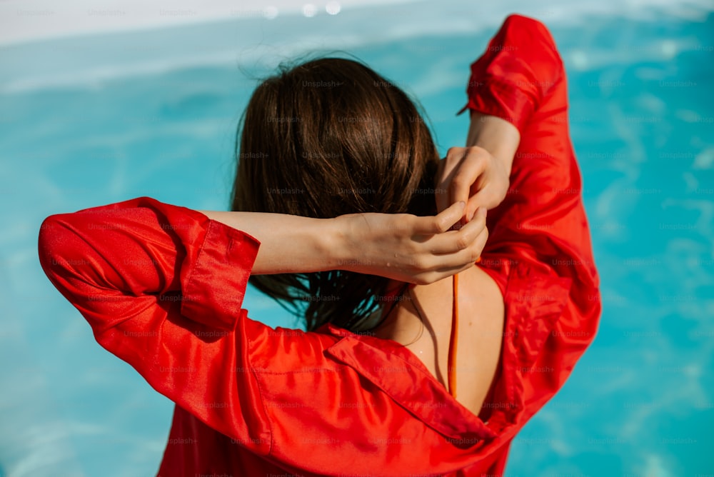 a woman in a red top standing in front of a pool