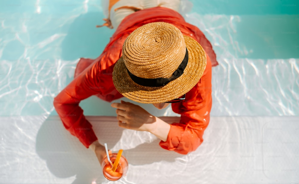 a person wearing a straw hat sitting in a pool