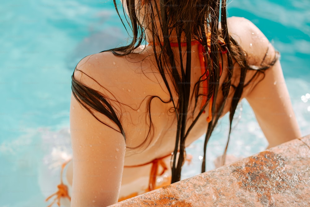 a woman with wet hair standing next to a swimming pool