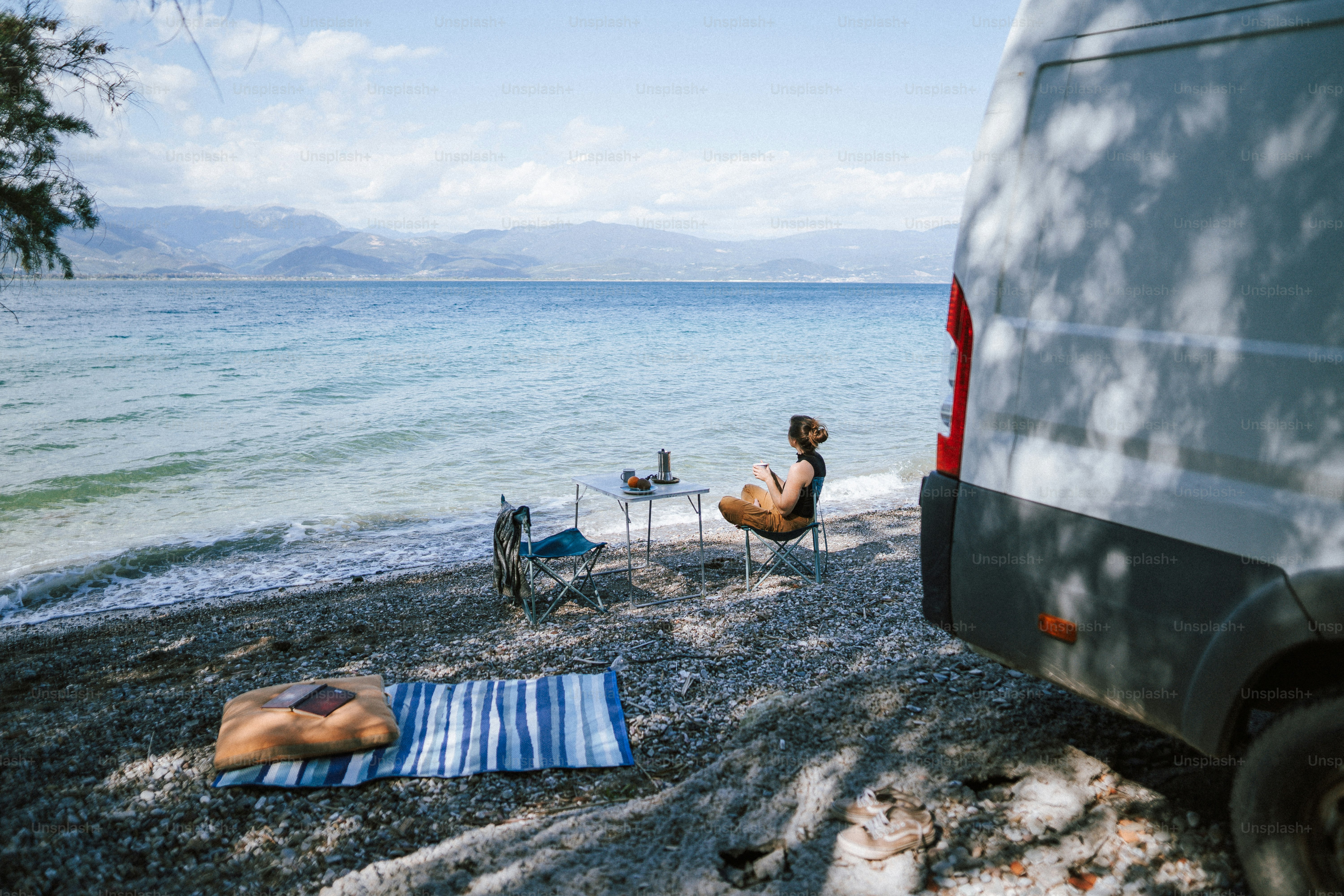 A van parked on a beach next to a body of water photo – Beach Image on ...