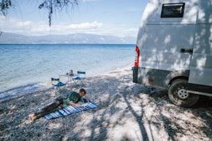 a man laying on a towel on a beach next to a van