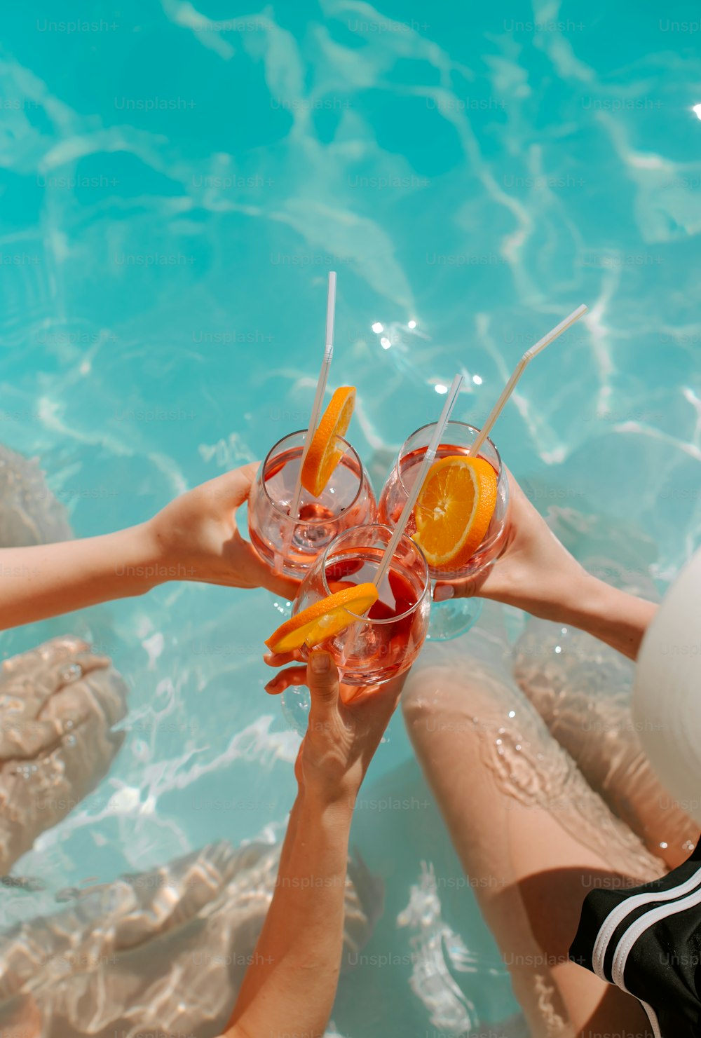a group of people toasting with drinks in a pool