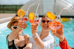 a group of women holding up wine glasses in front of a swimming pool