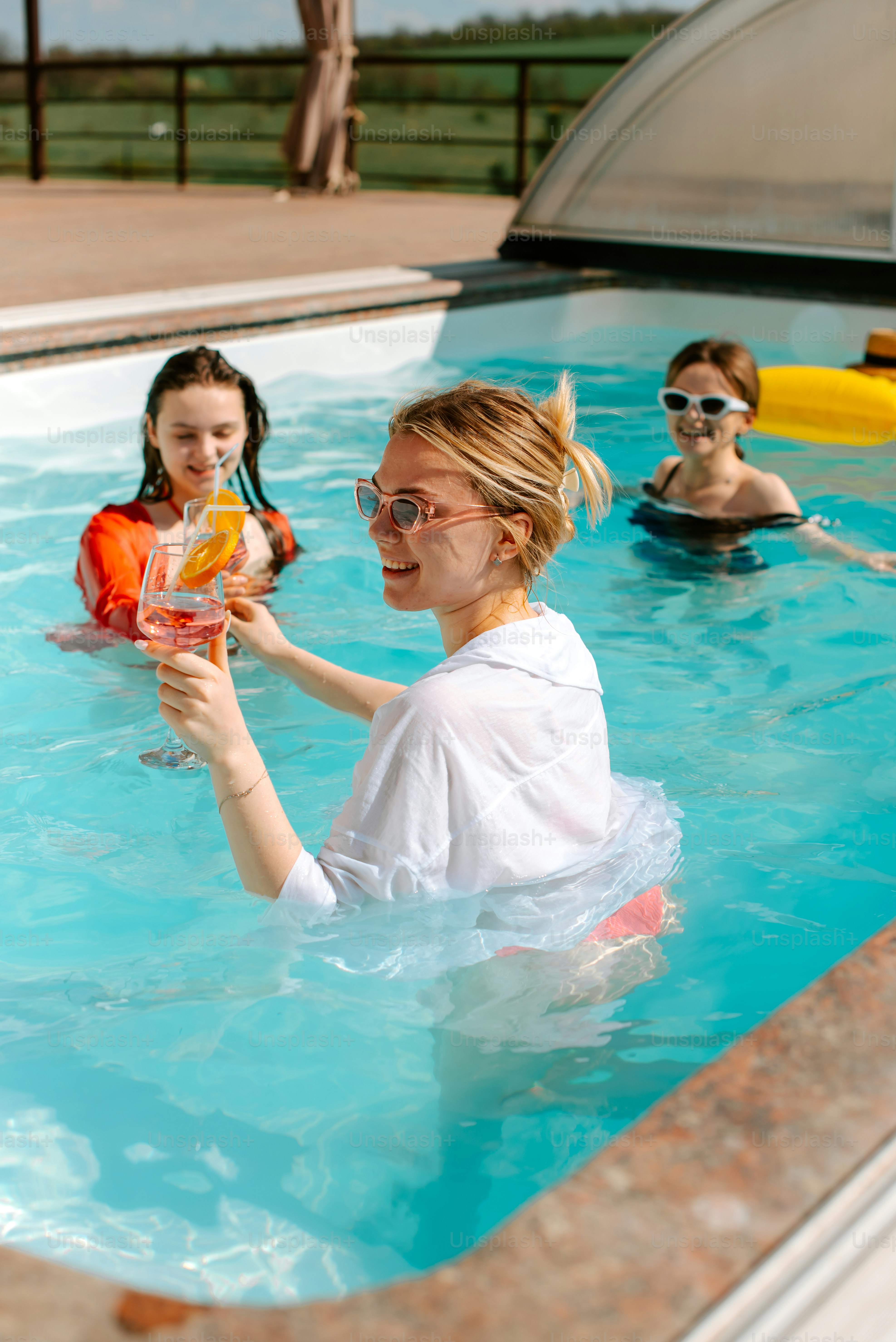 A woman holding a drink in a swimming pool photo – Summer party Image