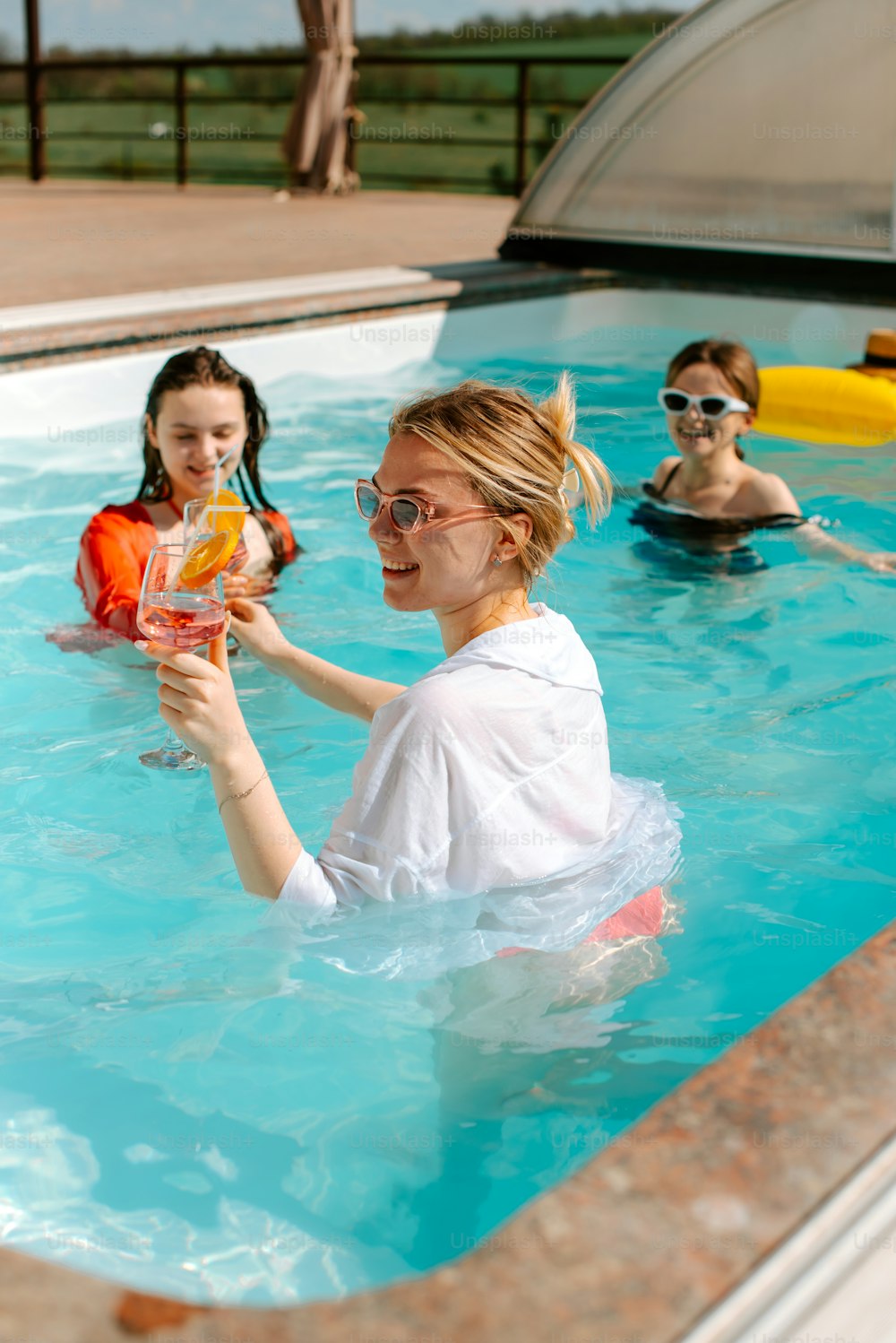 a woman holding a drink in a swimming pool
