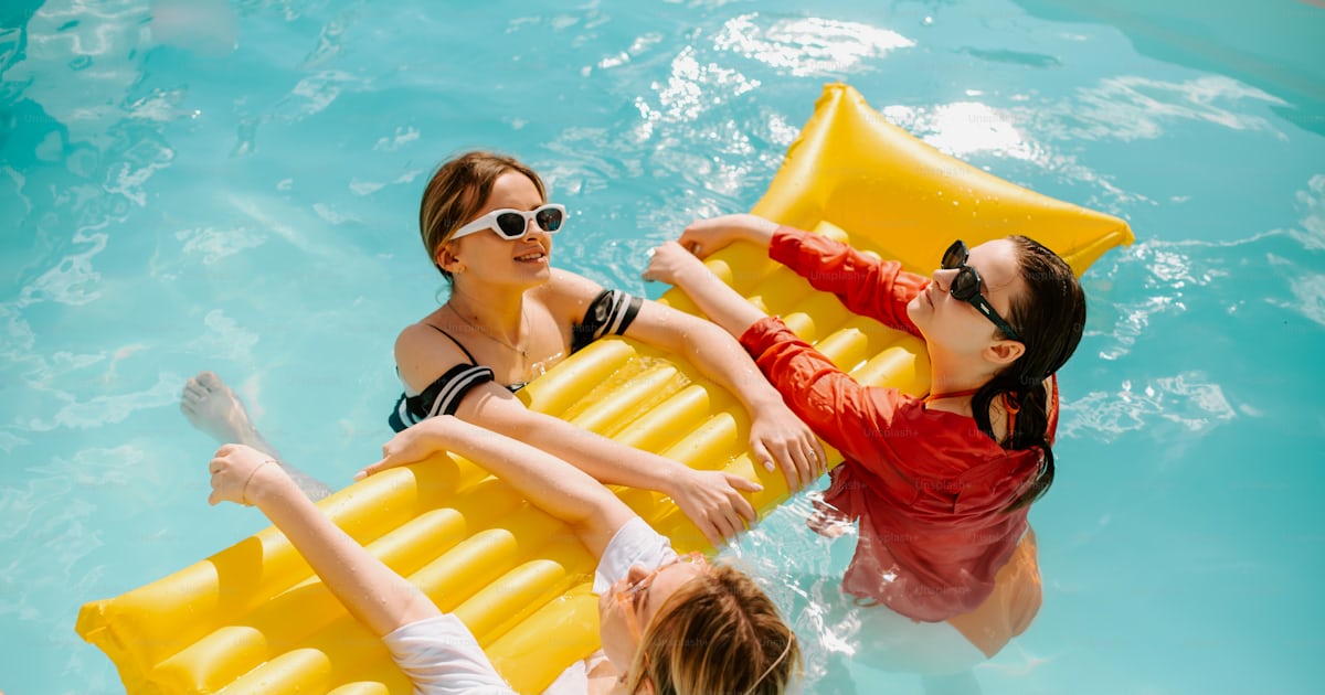 A group of people floating in a pool on inflatable rafts photo – People ...