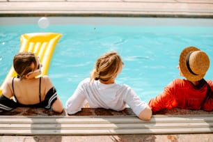 a couple of people sitting next to a swimming pool