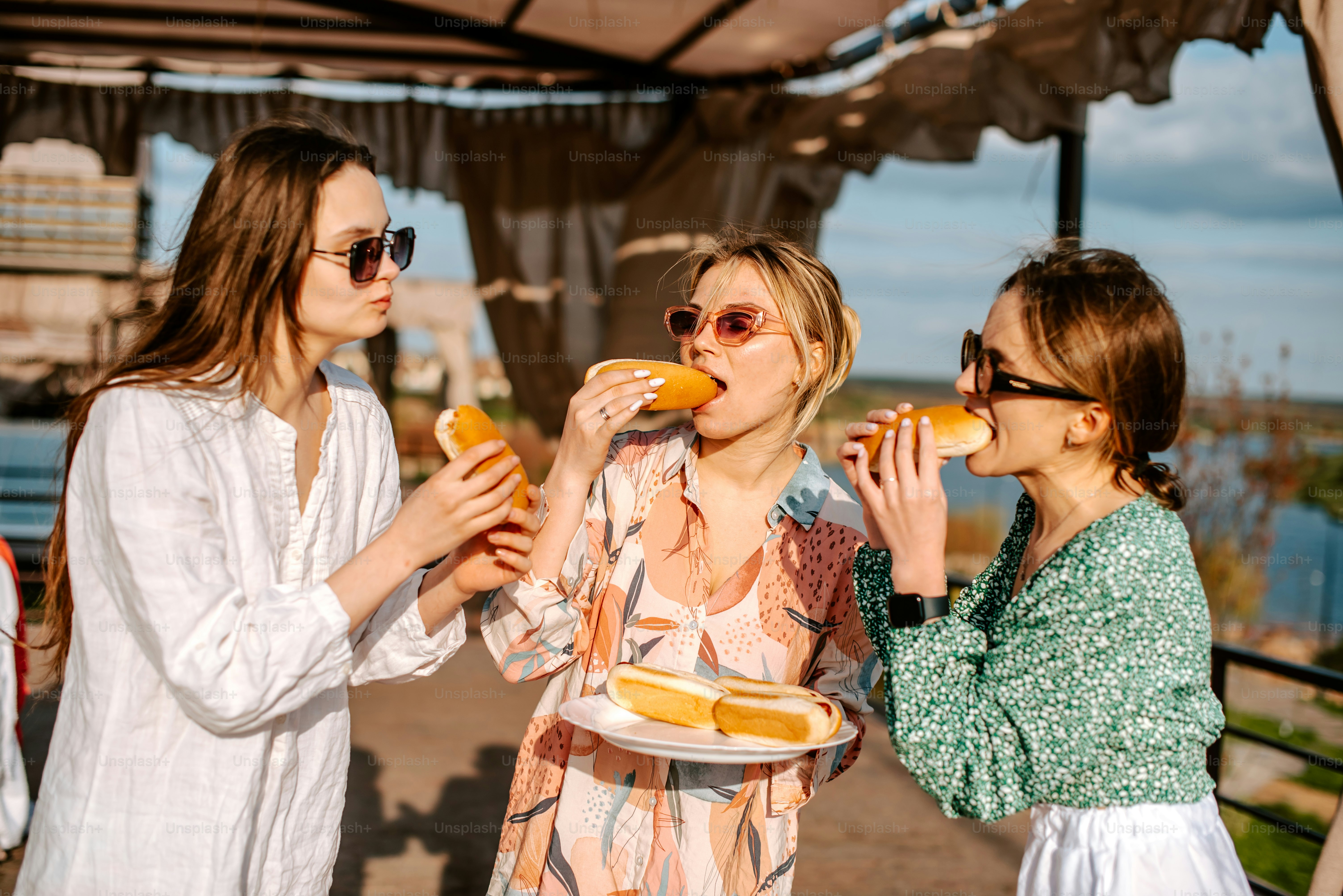 a group of women standing next to each other eating food