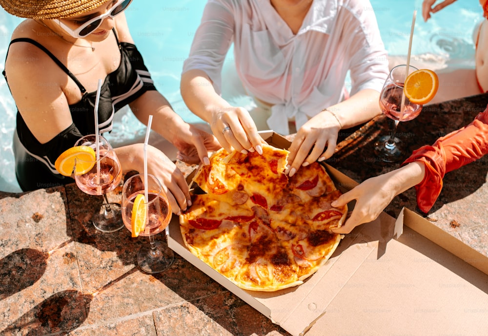 un gruppo di persone sedute intorno a un tavolo con pizza