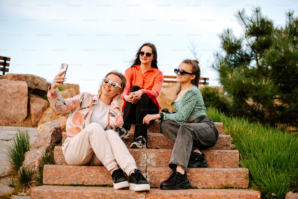 Tres mujeres sentadas en escalones tomándose una selfie