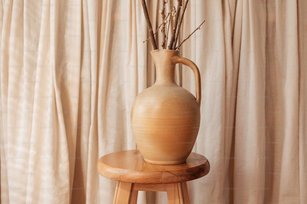 a vase sitting on a stool next to a curtain