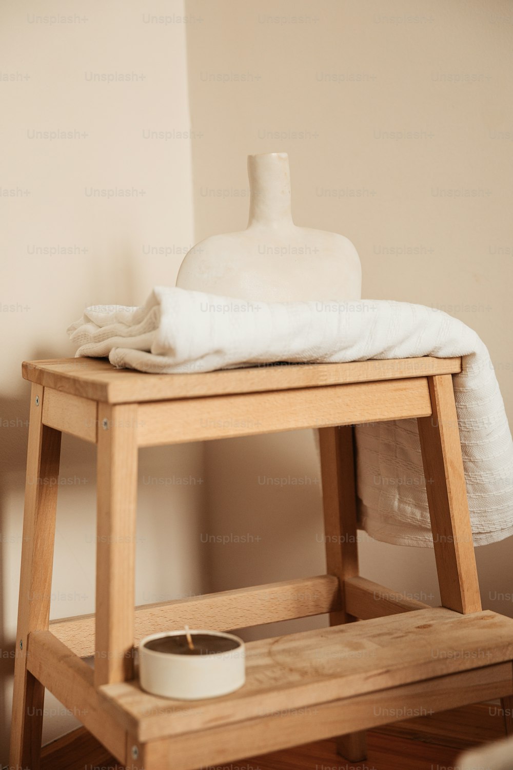 a white vase sitting on top of a wooden stool