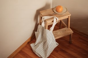 una naranja sentada encima de una mesa de madera junto a una bolsa