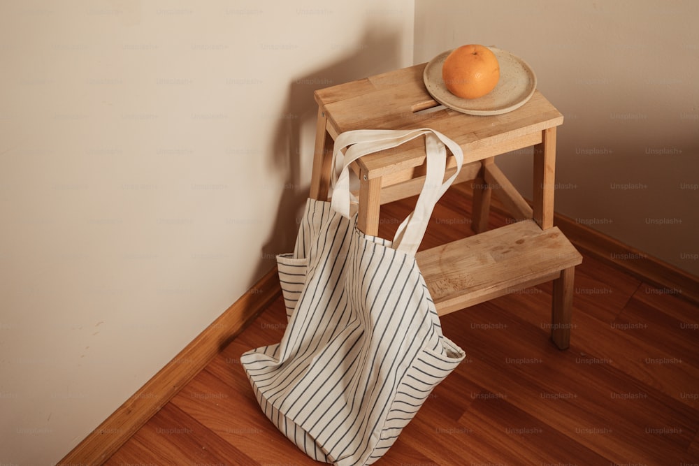 an orange sitting on top of a wooden table next to a bag