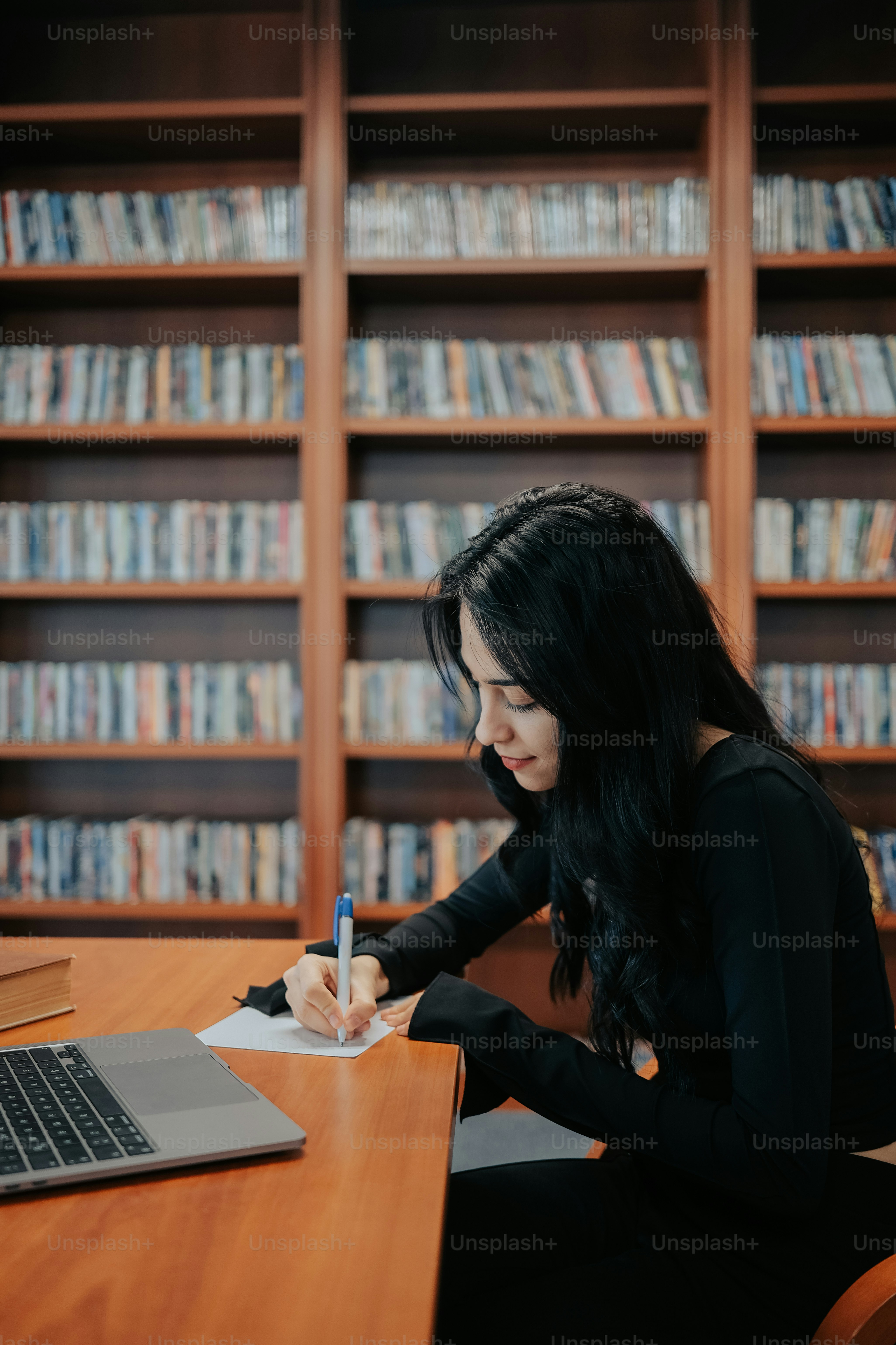 A woman sitting at a desk writing on a notebook photo – Taking notes ...